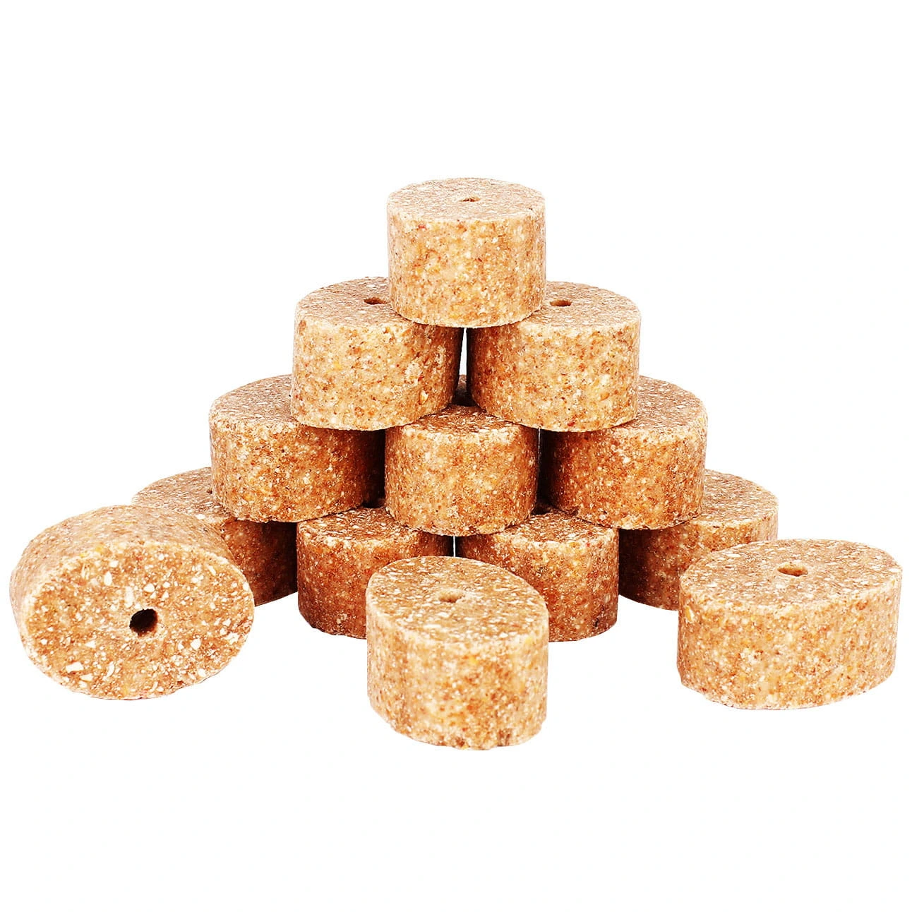 Cylindryczne granulki paszowe z otworem pośrodku, jasnobrązowe, ułożone w piramidę na białym tle.